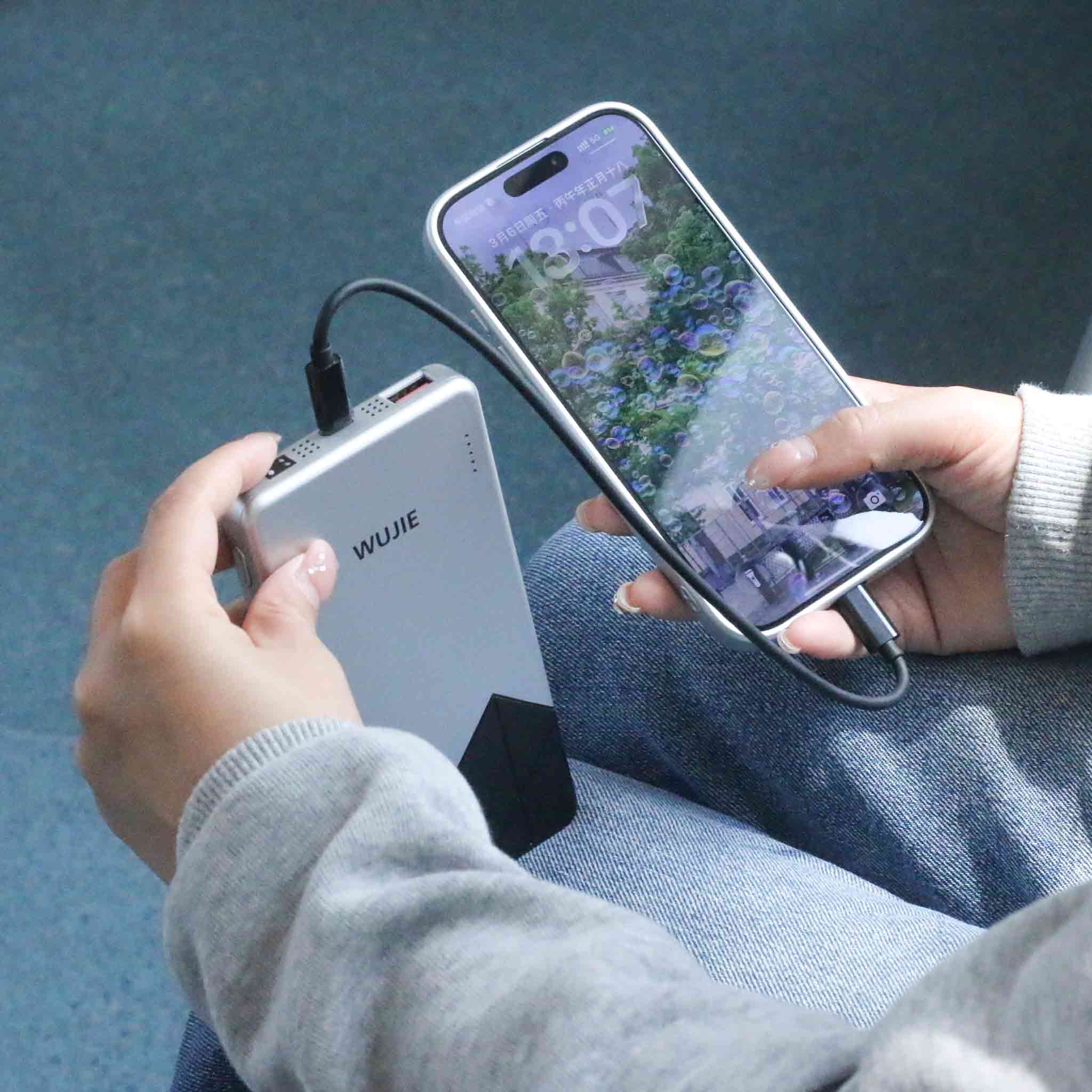Charging a phone via a WUJIE power bank represents the sustained energy and connectivity that technology offers during mobile moments.