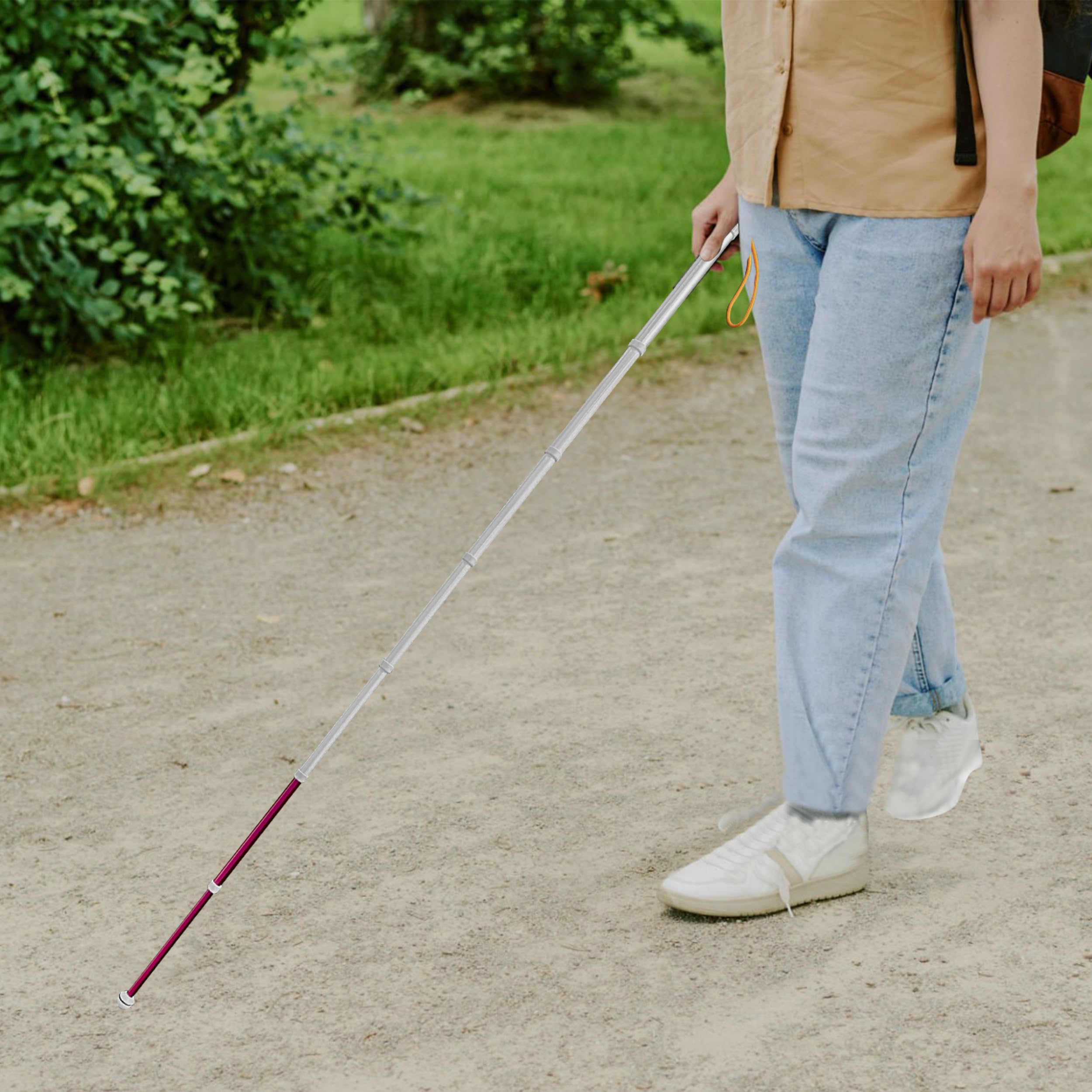 User navigating gravel outdoor path with retractable blind guide cane for independent mobility