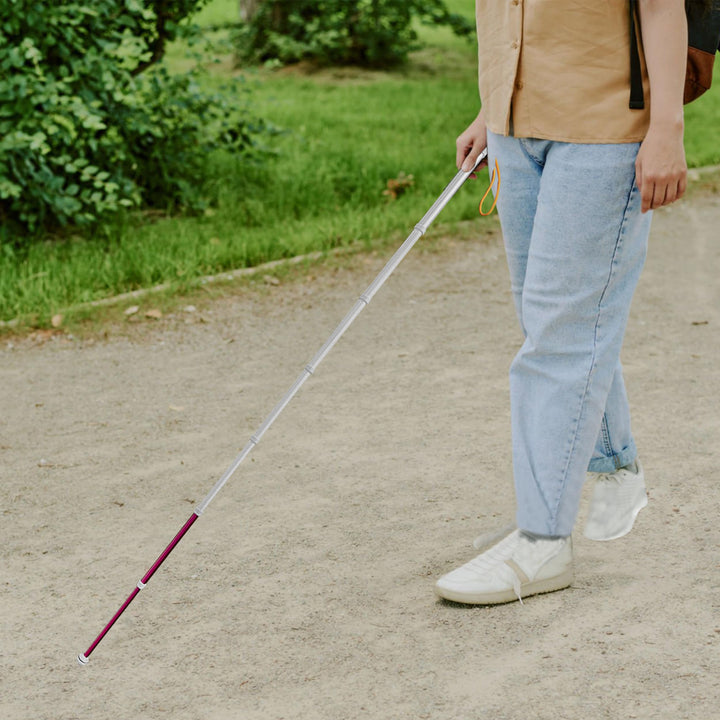 User navigating gravel outdoor path with retractable blind guide cane for independent mobility