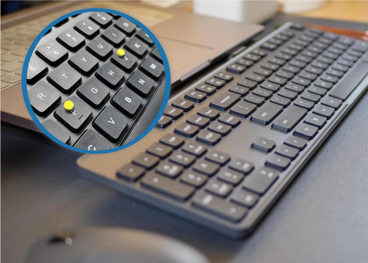 Yellow tactile bump dots applied on laptop keyboard keys for visually impaired users